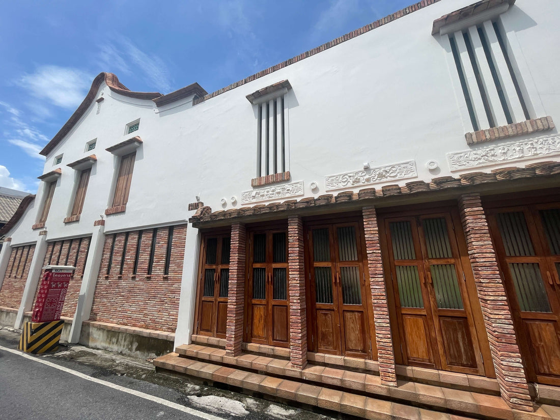 Maison commerçante de style Nanyang restaurée à Songkhla, avec des murs blanc cassé, des détails en briques, des volets en bois et des toits courbés, reflétant l’héritage chinois, malais et thaï. Architecture Nan Yang
